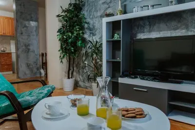 a table with a plate of food and orange juice at Apartman David in Ruma