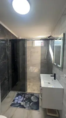 a bathroom with a shower and a sink and a mirror at Apartman Trg Lux in Arandjelovac