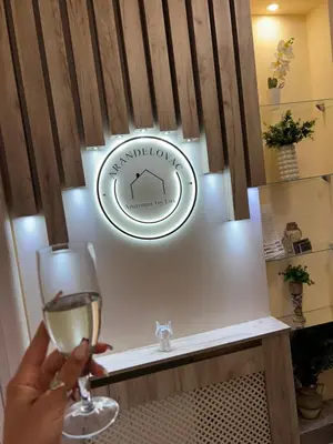 a person holding a glass of wine and a sign at Apartman Trg Lux in Arandjelovac