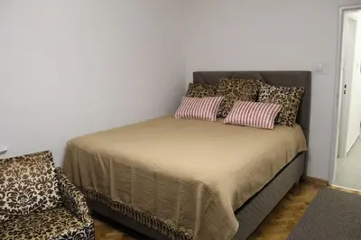 a bedroom with a bed with pillows and a chair at N&AA apartman in Belgrade
