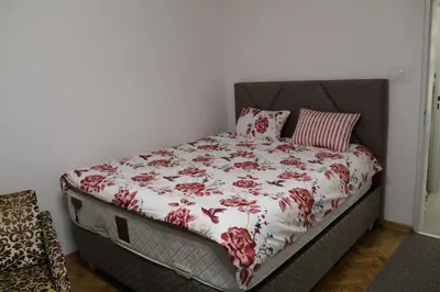 a bed with a red and white comforter on it at N&AA apartman in Belgrade