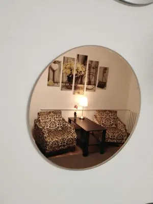 a mirror reflecting a living room with a table and a chair at N&AA apartman in Belgrade