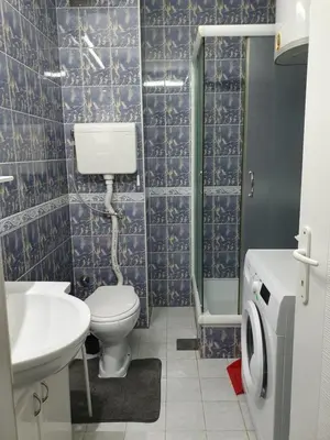 a bathroom with blue tiled walls and a toilet and a sink at AS Apartment in Tošin Bunar