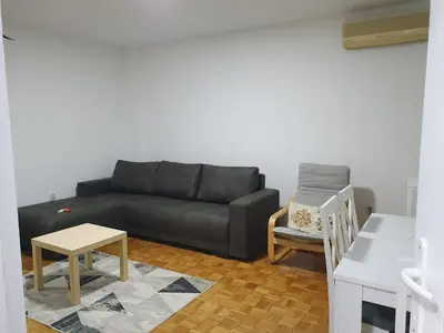 a living room with a black couch and a table at AS Apartment in Tošin Bunar