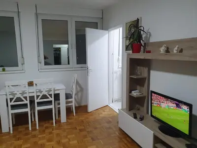 a living room with a television and a dining room table at AS Apartment in Tošin Bunar