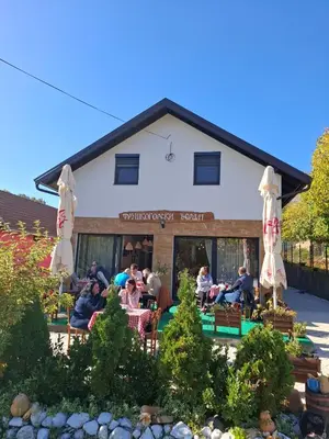 a group of people sitting at a restaurant with umbrellas at Fruškogorski Đeram in Grgeteg