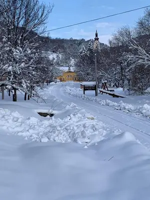 a path covered in snow with a bench and trees at Fruškogorski Đeram in Grgeteg