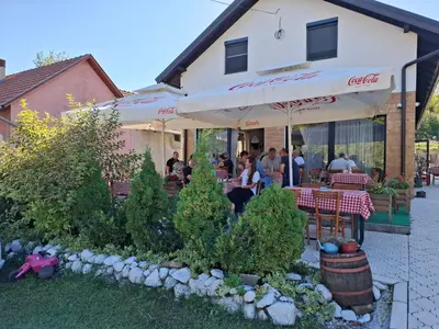 a restaurant with people sitting at tables under an umbrella at Fruškogorski Đeram in Grgeteg