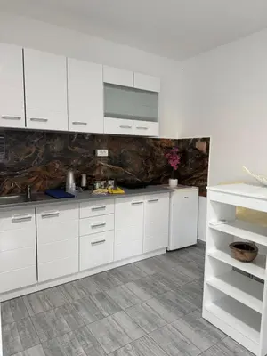 a white kitchen with white cabinets and a tile floor at Kares house in Belgrade