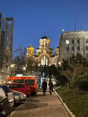 two people walking down a sidewalk in front of a building at Alexandar13 in Belgrade