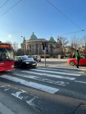 a red bus driving down a city street with cars at Alexandar13 in Belgrade