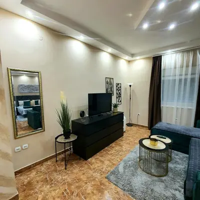 a living room with a blue couch and a tv at Emerald Apartment Belgrade in Senjak (historical)