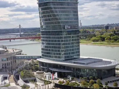 a tall building with a sign on it next to a river at Beograd na Vodi - BW ARCADIA LUXURY in Belgrade