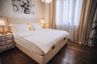 a bedroom with a bed with white sheets and a window at Beograd na Vodi - BW ARCADIA LUXURY in Belgrade