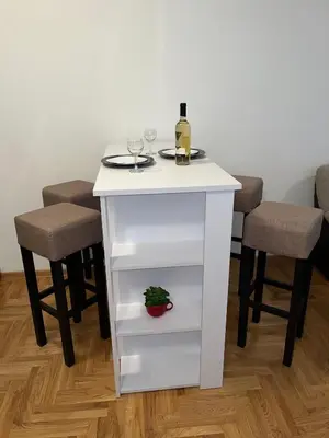 a white table with a bottle of wine and two stools at Fimiso in Borča