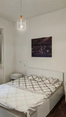 a bed in a white room with a picture on the wall at ZELENI VENAC Studio & Apartment in Belgrade