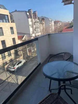 a balcony with a table and chairs and a view of a street at Vanja's place in Belgrade