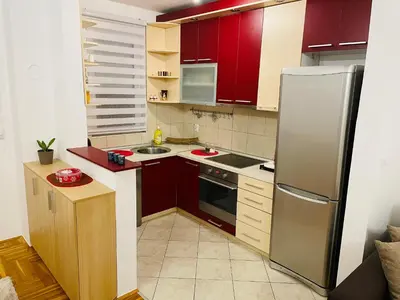 a kitchen with red cabinets and a stainless steel refrigerator at Jolly Apartment - Belgrade in Belgrade