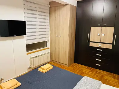 a bedroom with a bed and a tv and a closet at Jolly Apartment - Belgrade in Belgrade