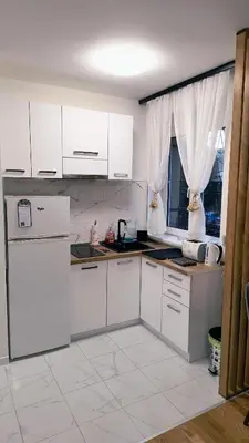 a white kitchen with white cabinets and a window at TALIJA in Vračar (historical)