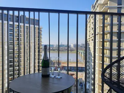 a bottle of wine sitting on a table on a balcony at Belgrade Waterfront Apartment - Beograd na vodi in Belgrade