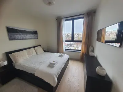 a bedroom with a large bed and two windows at Belgrade Waterfront Apartment - Beograd na vodi in Belgrade