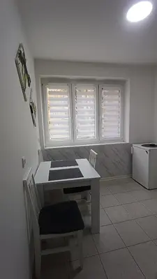 a kitchen with a table and chairs and two windows at Savska - Apartment in Sajmište