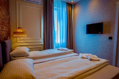 two beds in a hotel room with a tv on the wall at Miha Premium Apartment in Belgrade