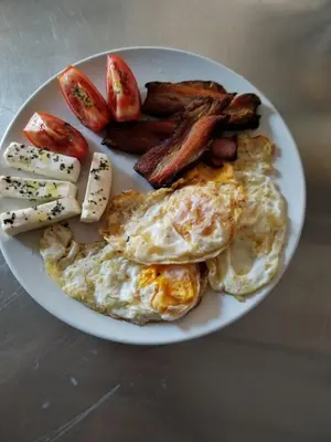 a plate of breakfast food with eggs bacon and sausage at Hotel Villa Sarto in Belgrade