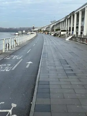an empty street next to the water with a bridge at Skyway Apartment Belgrade Waterfront in Belgrade