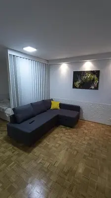 a living room with a blue couch in a room at Trgovacka Zarkovo - Apartman in Žarkovo