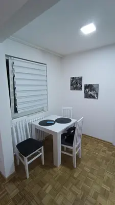 a white table and chairs in a room with a window at Trgovacka Zarkovo - Apartman in Žarkovo