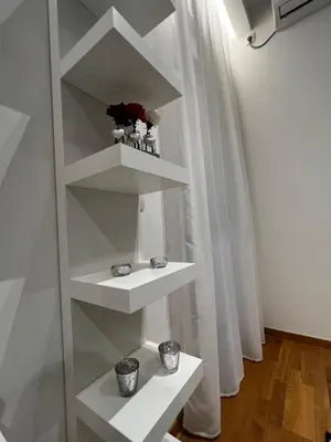 a white book shelf with two cups on it at Real Apartment Banovci in Novi Banovci