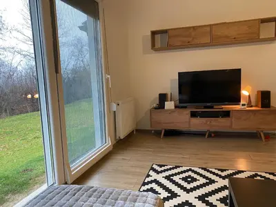 a living room with a tv and a large window at Kućica u šumici in Stojnik