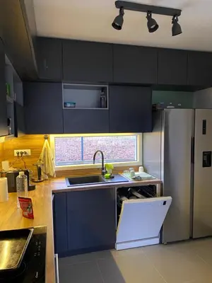 a kitchen with black cabinets and a stainless steel refrigerator at Kućica u šumici in Stojnik