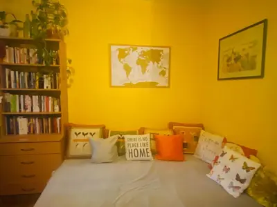 a yellow room with a bed with pillows on it at Funkcionalna garsonjera u Zemunu in Zemun