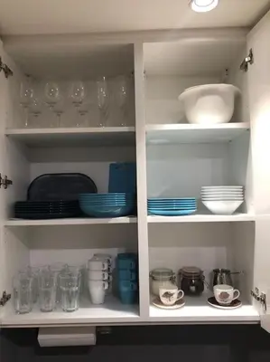 a white cabinet filled with plates and bowls and glasses at Lovely BW Metropolitan studio in Belgrade