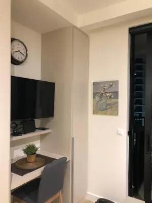 a room with a desk with a tv and a clock at Lovely BW Metropolitan studio in Belgrade