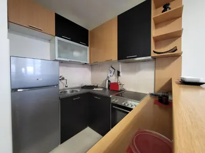 a kitchen with black cabinets and a stainless steel refrigerator at GREY apartment in Belgrade
