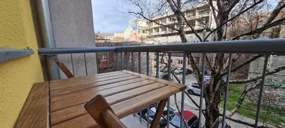 a wooden bench sitting on a balcony with a tree at JULIJA apartment in Belgrade