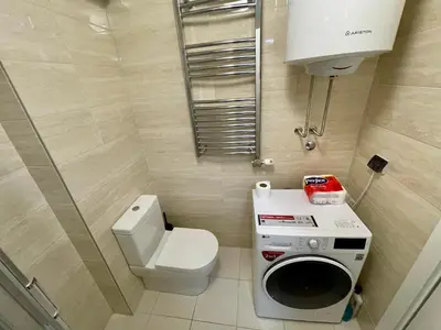 a small bathroom with a toilet and a washing machine at Apartment Maximus II lux in Novi Beograd