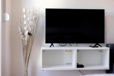 a flat screen tv sitting on a white entertainment center at Altina Connect - all new, parking, Netflix in Belgrade