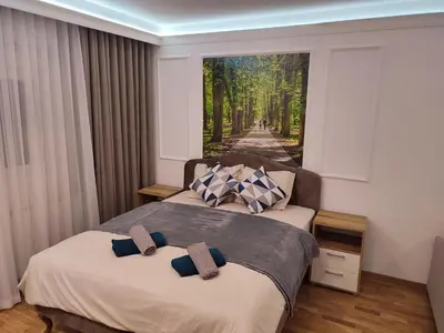 two beds in a room with a painting on the wall at TiD Apartman LUX in Arandjelovac