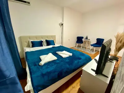 a bedroom with a bed with blue sheets and a tv at Apartman Espo in Vračar (historical)