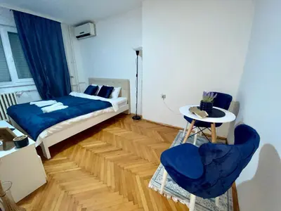 a bedroom with a bed and a table and two chairs at Apartman Espo in Vračar (historical)
