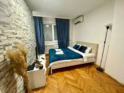 a bedroom with a bed and a stone wall at Apartman Espo in Vračar (historical)