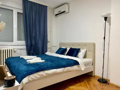 a bedroom with a bed with blue blankets and pillows at Apartman Espo in Vračar (historical)