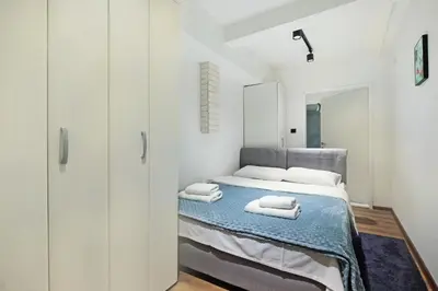 a white bedroom with a bed and a mirror at Apartment Paradise Resavska in Belgrade