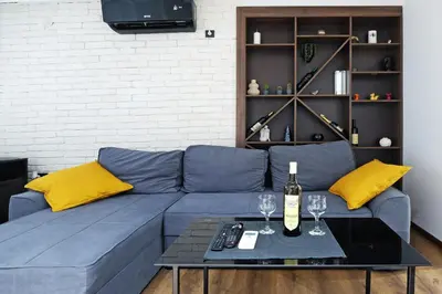 a living room with a blue couch with yellow pillows at Apartment Paradise Resavska in Belgrade