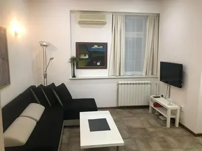 a living room with a black couch and a tv at Saint Sava studio in Belgrade